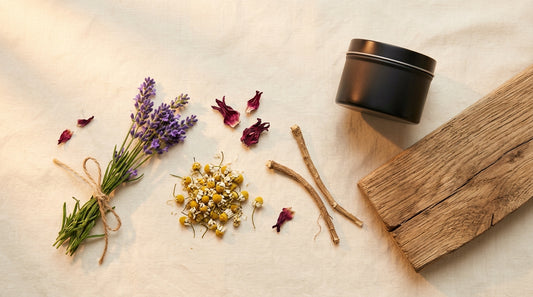 Lavender sprigs, chamomile flowers, hibiscus petals, valerian root, and a small matte black tin on warm cream linen